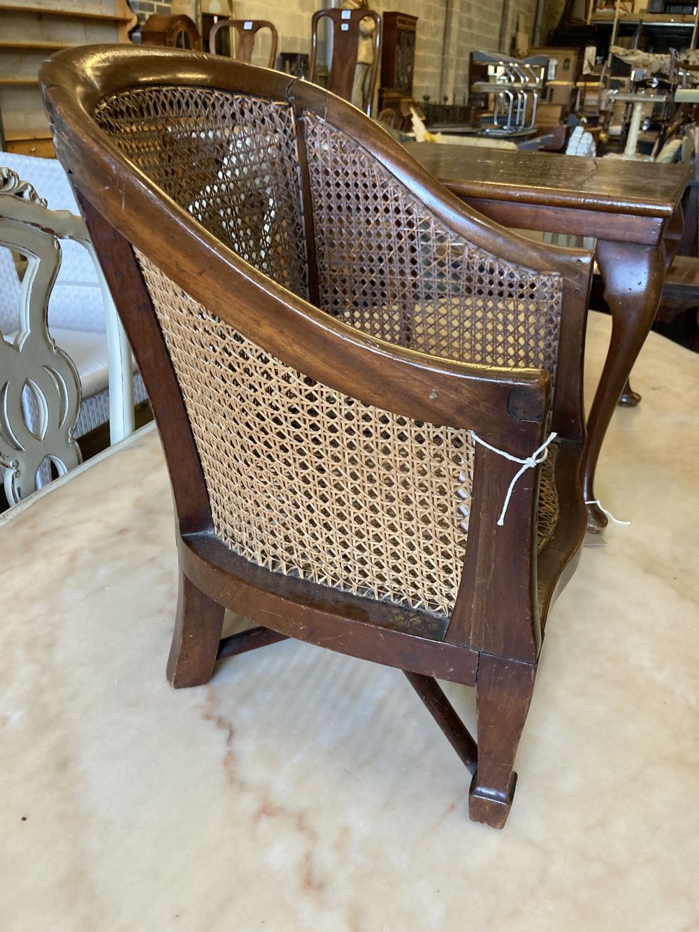 A childs caned mahogany bergere on table stand